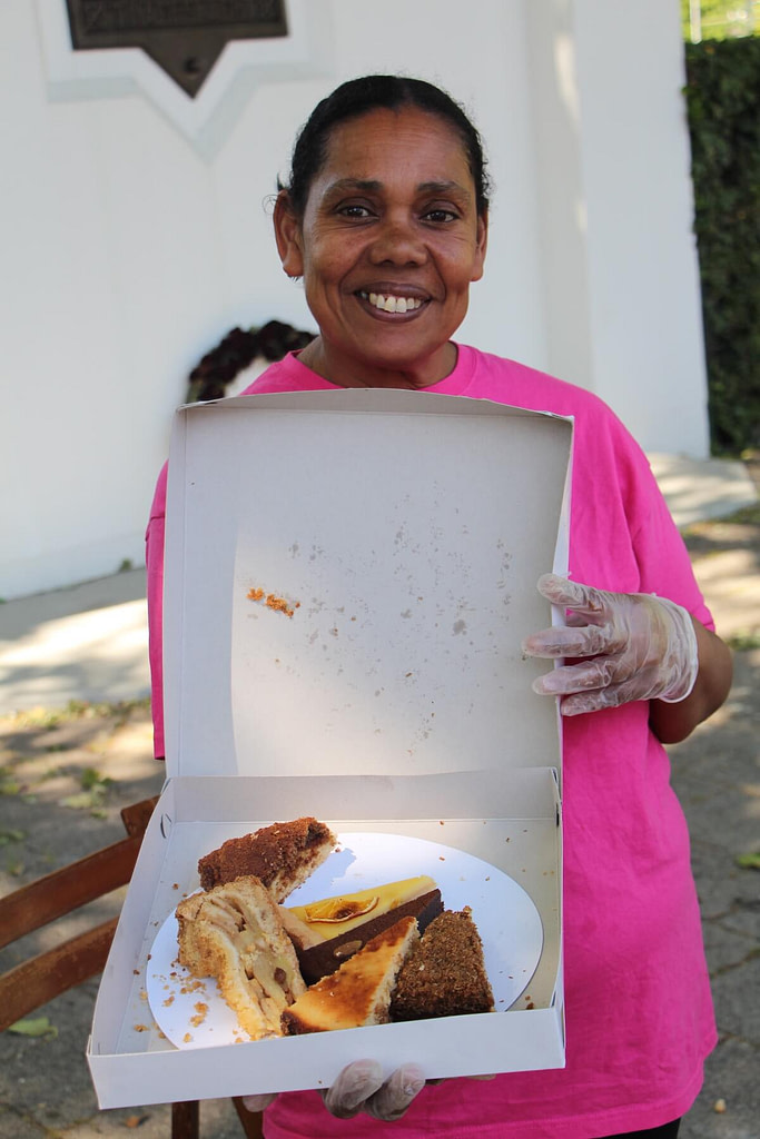 Een vrijwilliger biedt taart aan bij Serve the City van Geloven in Spangen